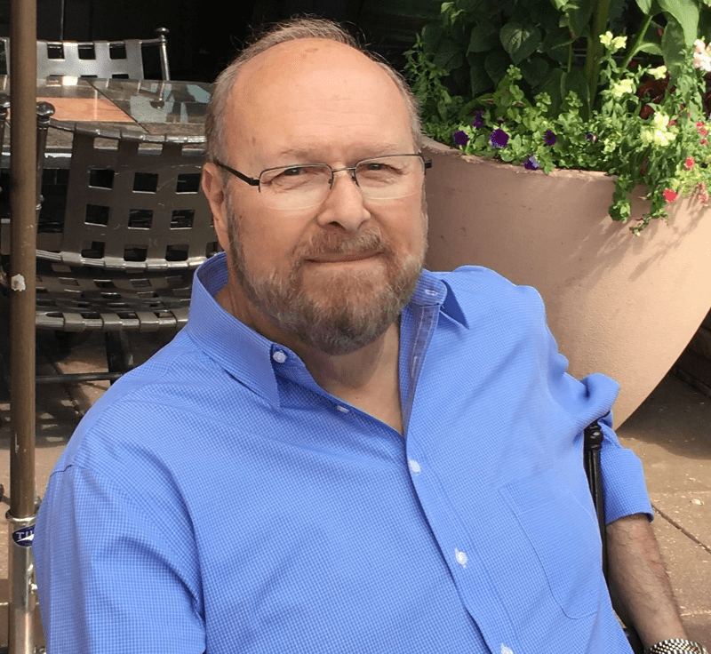 A man in a blue shirt sitting in a chair.