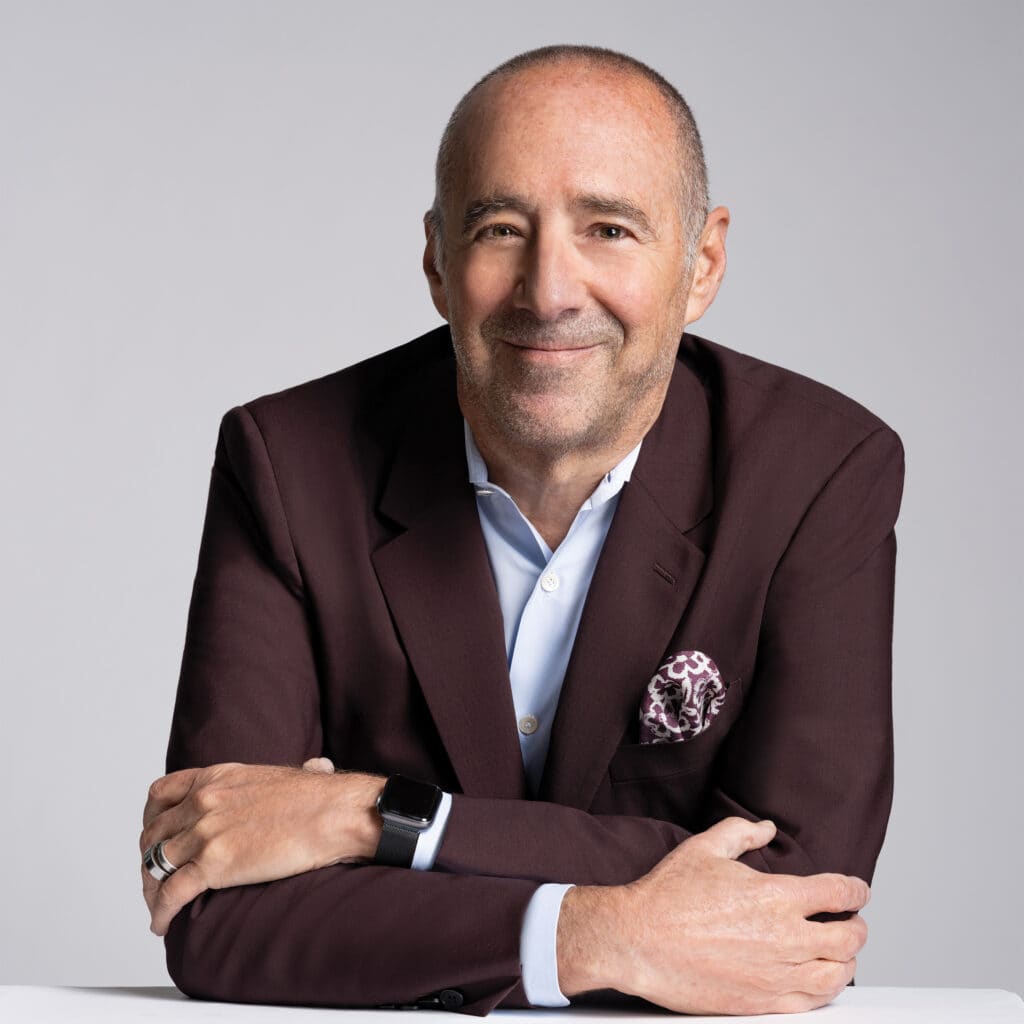 A man in a burgundy suit is posing for a photo.