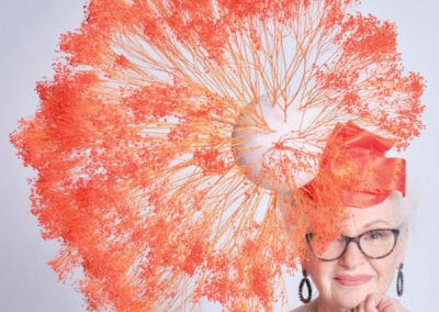 An older woman wearing glasses and an orange hat.