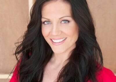 A woman with long black hair smiling in a red shirt.