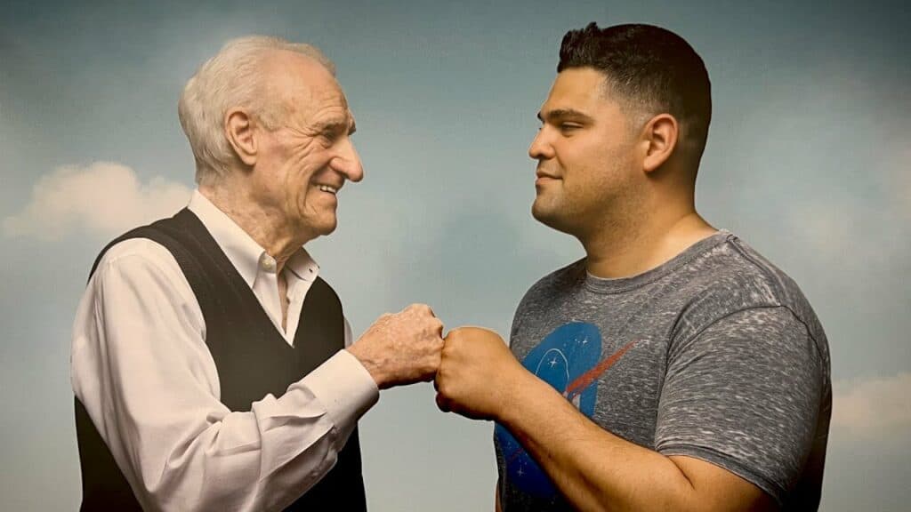 An older man and a younger man are standing next to each other.