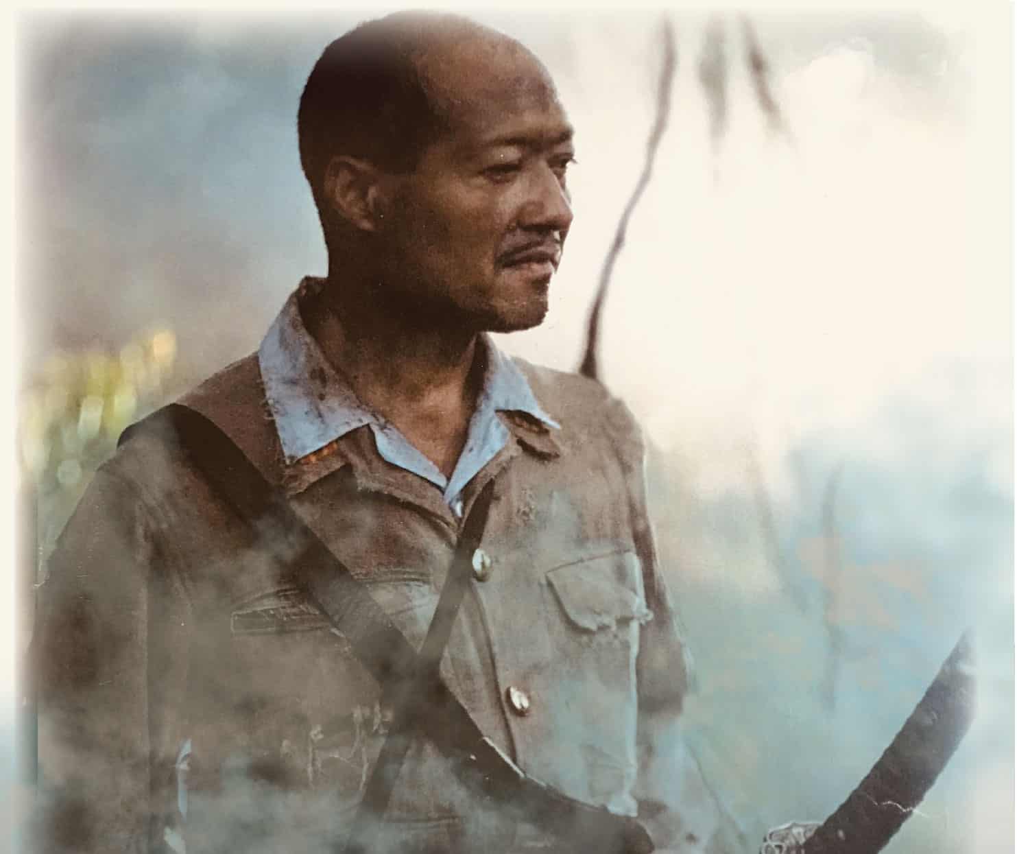 A man holding a gun in front of smoke.