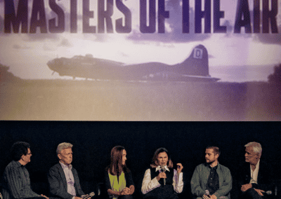 Group of six people on a panel discussion stage with a “Masters of the Air” banner above, featuring an image of a military plane in the background.