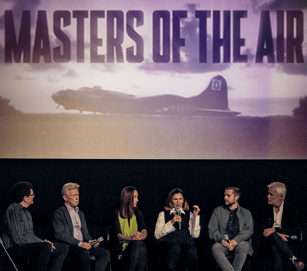 Group of six people on a panel discussion stage with a “Masters of the Air” banner above, featuring an image of a military plane in the background.